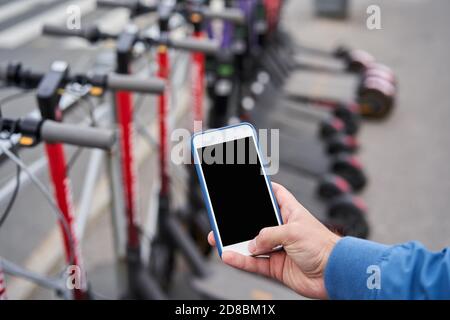 Elektroroller Verleih über Smartphone-App mit Hilfe von QR-Code. Stockfoto