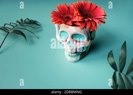 Bemalter Keramikschädel mit leuchtend roten Gänseblümchen Blumen. Dia de los Muertos Dekoration. Stockfoto