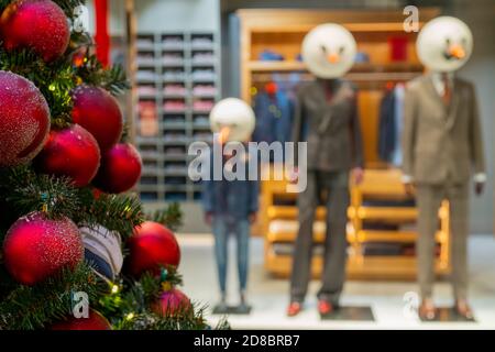 Weihnachtsbaum mit roten Kugeln verziert, Schaufensterpuppen mit Schneemännern Köpfe im Hintergrund Stockfoto