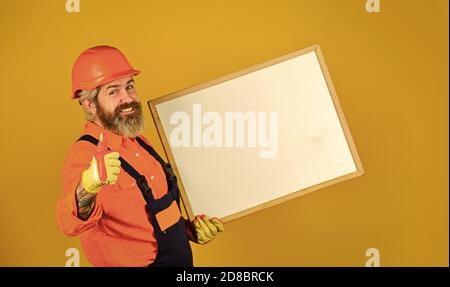 Männlicher Bauarbeiter. Kopierraum. Planung eines neuen Projekts. Mann mit Präsentation. Builder mit Flipchart. Architekt Arbeiter halten Flipchart. Präsentation Flipchart bei der Sitzung. Daumen hoch für Erfolg. Stockfoto