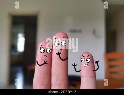 Zwei Finger sind als drei Personen dekoriert. Die Eltern machen sich Sorgen um ihr ungezogenes Kind. Stockfoto