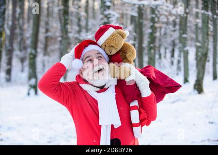 Weihnachtsmann mit Teddybär Spaziergang im Winter Berge Schnee in Weihnachten. Stockfoto