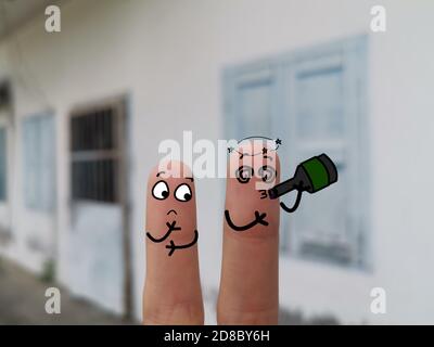 Zwei Finger sind als zwei Personen auf der Straße geschmückt. Einer von ihnen trinkt Alkohol. Stockfoto
