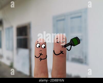 Zwei Finger sind als zwei Personen auf der Straße geschmückt. Einer von ihnen trinkt Alkohol. Stockfoto