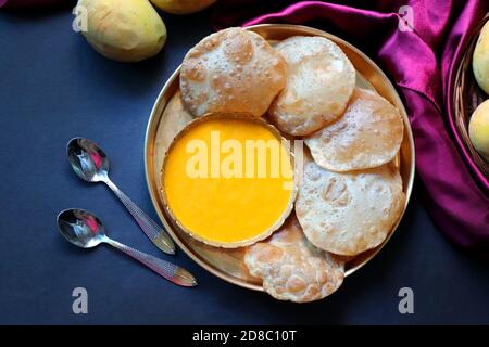 Indisches Essen - Aamras ist ein süßes Gericht, das aus dem Fruchtfleisch der Alphonso-Mangofrucht hergestellt wird. Serviert mit heißen puri/Poori. Süßes Mango-Püree. Stockfoto