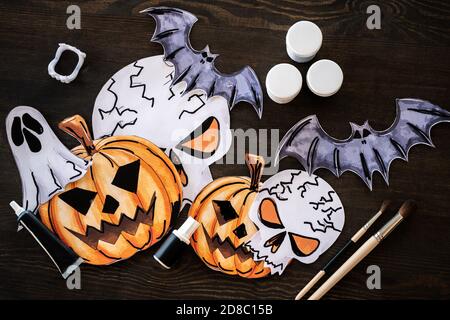 High-Angle-Ansicht von kreativen Zeichnungen von Halloween-Figuren, Gouache Gläser und Pinsel auf Holztisch im Kunststudio Stockfoto