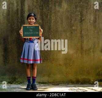 Durgapur, Indien - Oktober 15,2020. Ein kleines indisches ländliches Mädchen mit einem grünen Brett geschrieben ' Recht auf Bildung ', EIN Konzept Bild. Stockfoto