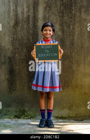 Durgapur, Indien - Oktober 15,2020. Ein kleines indisches ländliches Mädchen mit einem grünen Brett geschrieben ' Recht auf Bildung ', EIN Konzept Bild. Stockfoto