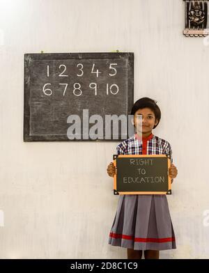 Durgapur/Indien – Oktober 15,2020. Ein Grundschulmädchen mit einem Green Board geschrieben "Recht auf Bildung" in einem Klassenzimmer. Ein Konzeptbild. Stockfoto