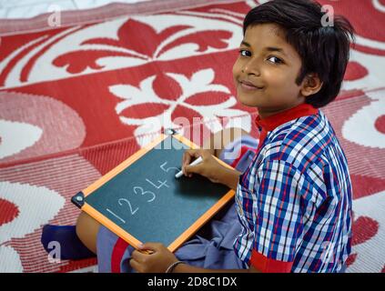 Durgapur/Indien – Oktober 15,2020. Eine hübsche Studentin schreibt Alphabete und lächelt an der Kamera. Selektiver Fokus wird verwendet. Stockfoto