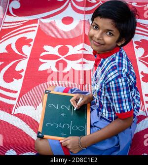 Durgapur/Indien – Oktober 15,2020. Eine hübsche Studentin schreibt Alphabete und lächelt an der Kamera. Selektiver Fokus wird verwendet. Stockfoto