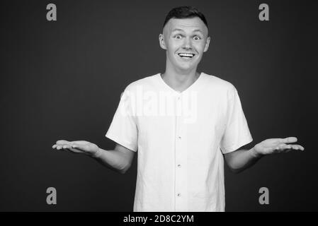 Junger Mann mit weißem Hemd vor grauem Hintergrund Stockfoto