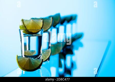 Tequila und Kalkscheiben auf blauem Grund. Stockfoto