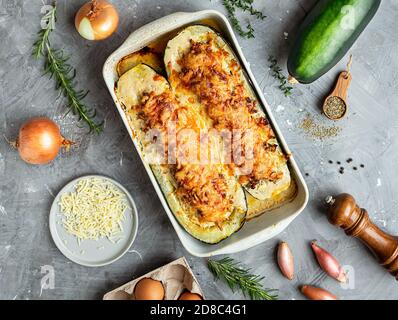 Hausgemachte gefüllte Zucchini, gebacken mit Fleisch, Zwiebeln, Eschalot, Knoblauch, Eier, Kräuter, Käse in Backform auf dem grauen Hintergrund. Draufsicht Stockfoto