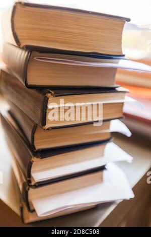 Vertikale Aufnahme von gestapelten Büchern mit Lesezeichen und Notizen Die Tabelle Stockfoto