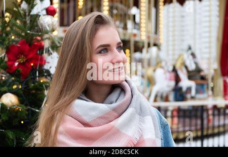 Happy junge blonde Mädchen auf dem Hintergrund des Weihnachtsmarktes. Neujahrsstimmung in der Großstadt. Weihnachten oder Neujahr Konzept. Stockfoto