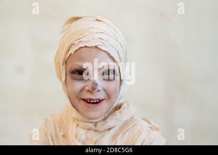 Porträt von glücklich unbeschwerten Jungen mit Bandagen wie Mama lachen vor isoliertem Hintergrund bedeckt, Halloween-Konzept Stockfoto