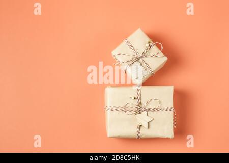 Zwei Weihnachtsgeschenke in Bastelpapier auf Terrakotta-Hintergrund eingewickelt. Speicherplatz kopieren. Draufsicht. Stockfoto