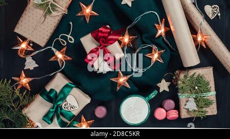 Weihnachten flach legen mit Handwerk Geschenkboxen, Girlande Lichter und Dekorationen auf dunklem Holzhintergrund Stockfoto