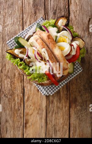 Israelisches Fastfood-Sabich-Sandwich mit Gemüse, Eiern und Tahini-Nahaufnahme auf dem Tisch. Vertikale Draufsicht von oben Stockfoto