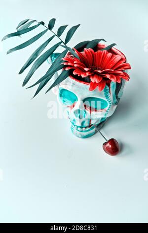 Totenkopf in Gesichtsmaske mit leuchtend roten Gerbera Gänseblümchen Blumen. Dia de los Muertos. Stockfoto