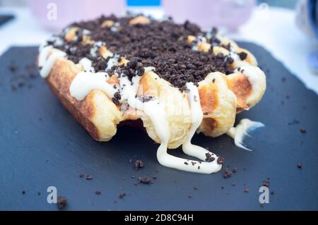 Viereckige Waffel mit weißer Schokoladenauflage und Plätzchen gepudert bedeckt. Nahaufnahme Stockfoto