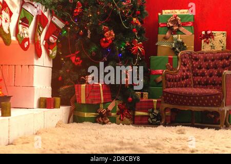 Beleuchtet weißen Stein Kamin mit Geschenken unter dem Baum, Vintage-Stuhl und verstecken dekoriert. Stockfoto