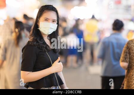 Asiatische weibliche tragen chirurgische Maske während der Reise in Nachtmarkt Neuer normaler Reiselebensstil in Thailand Stockfoto