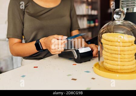 Seitenansicht einer nicht erkennbaren Frau, die mit NFC-Technologie bezahlt Auf Kreditkarte im Café Stockfoto
