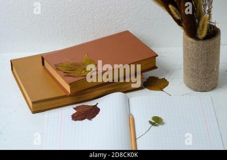 Notizbuch mit einem Lesezeichen aus vierblättrigen Kleeblatt auf dem Hintergrund eines Herbststraußes und Blättern Selektiver Fokus. Stockfoto