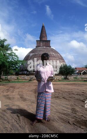 Ein Souvenirverkäufer steht vor Jetavanaramaya Dagoba ist ein Stupa, oder buddhistische Reliquiendenkmal, in den Ruinen des Jetavana Klosters in der alten buddhistischen Heiligen Stadt Anuradhapura, Sri Lanka Stockfoto