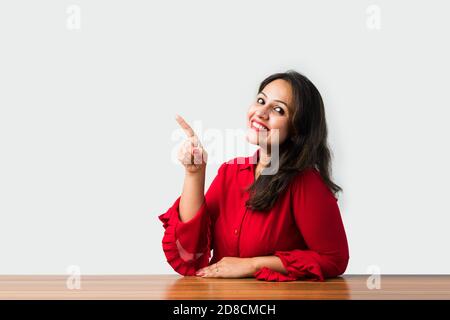 Indisch asiatisch hübsch Frau stehend am Tisch ruht Kinn auf Hände Stockfoto