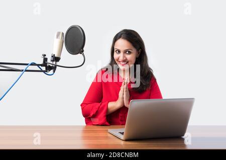 Hübsche Inderin spricht vor dem Mikrofon, während sie einen Videoblog für seine Abonnenten aufnimmt und dabei die Kamera anschaut Stockfoto