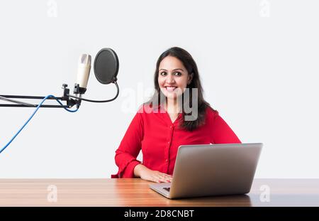 Hübsche Inderin spricht vor dem Mikrofon, während sie einen Videoblog für seine Abonnenten aufnimmt und dabei die Kamera anschaut Stockfoto