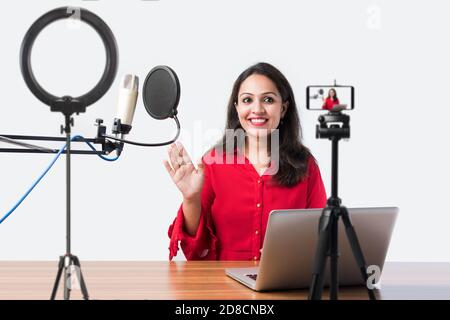 Hübsche Inderin spricht vor dem Mikrofon, während sie einen Videoblog für seine Abonnenten aufnimmt und dabei die Kamera anschaut Stockfoto