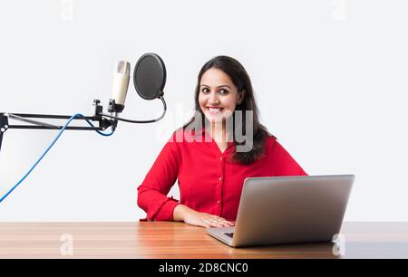 Hübsche Inderin spricht vor dem Mikrofon, während sie einen Videoblog für seine Abonnenten aufnimmt und dabei die Kamera anschaut Stockfoto