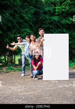 Asiatische indische College-Studenten Halten oder zeigen leere Whiteboard oder Plakat in Universität Campus, im Freien erschossen Stockfoto