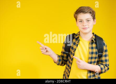 Glücklich junge Schuljunge in casual Hemd zeigt nach oben über gelben Hintergrund. Stockfoto