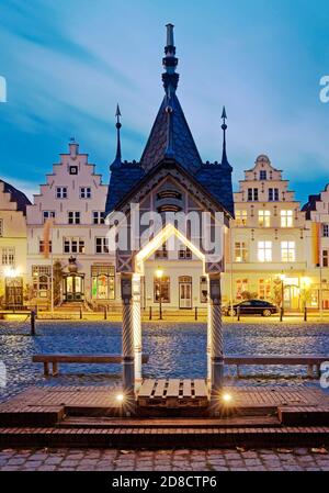 Historische Wasserpumpe auf dem Marktplatz vor Häusern mit Stufengiebeln am Abend, Deutschland, Schleswig-Holstein, Nordfriesland, Stockfoto