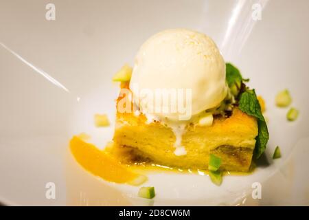 apfelstrudel serviert mit einer einzigen Kugel Vanilleeis Sahne und gehackte Äpfel und Minze Stockfoto