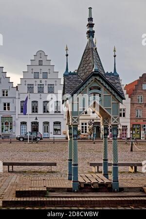 Historische Wasserpumpe auf dem Marktplatz vor Häusern mit Stufengiebeln, Deutschland, Schleswig-Holstein, Nordfriesland, Friedrichstadt Stockfoto