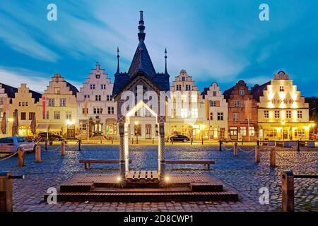 Historische Wasserpumpe auf dem Marktplatz vor Häusern mit Stufengiebeln am Abend, Deutschland, Schleswig-Holstein, Nordfriesland, Stockfoto