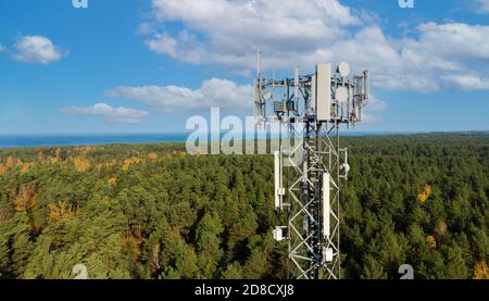 Telekommunikationsturm mit Antennen für 5g-Netz auf Wald und blauer Himmel Hintergrund. Mobile Internet-Übertragung Stockfoto