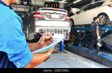 Mechaniker prüft die Motorreparaturliste in der Garage. Stockfoto