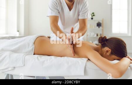 Masseur tut Rückenmassage für junge Frau mit Tapotement-Technik Zur Linderung von Muskelverspannungen Stockfoto