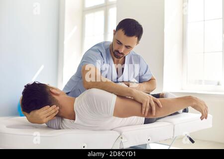 Chiropraktiker, Osteopath, Physiotherapeut oder manuelle Therapeut arbeiten mit jungen Mann in der modernen Klinik Stockfoto