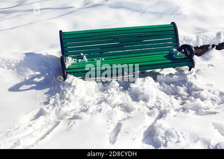 Leere grüne Bank im Schnee. Winter im Stadtpark Stockfoto