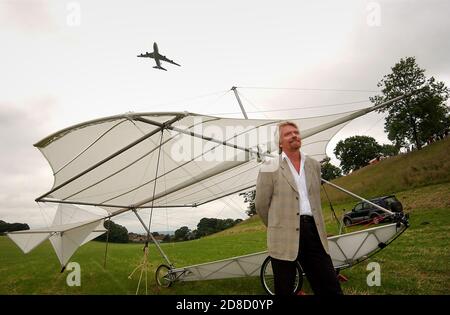 Richard Branson neben einer Nachbildung von Sir George Cayleys Segelflugzeug, mit einer Virgin Atlantic Boeing 747 (G-VAST), die über ihm fliegt, bevor er Cayle nachbaut Stockfoto