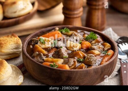 Rindereintopf mit Karotten und Kartoffeln in einer Holzschüssel Und Kekse im Hintergrund Stockfoto