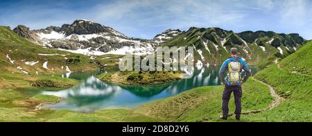 Wandermann steht am abgelegenen See hoch oben in den alpinen Bergen. Alpen, Bayern, Schrecksee. Stockfoto